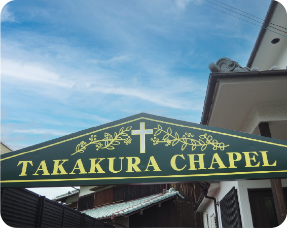 「takakura chapel」青空をバックにした高倉チャペルの入り口にある緑色の看板
